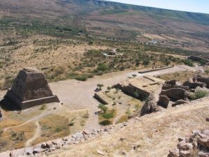 Vista de la pirámide votiva, y a la derecha, el juego de pelota con la clásica forma de i latina.